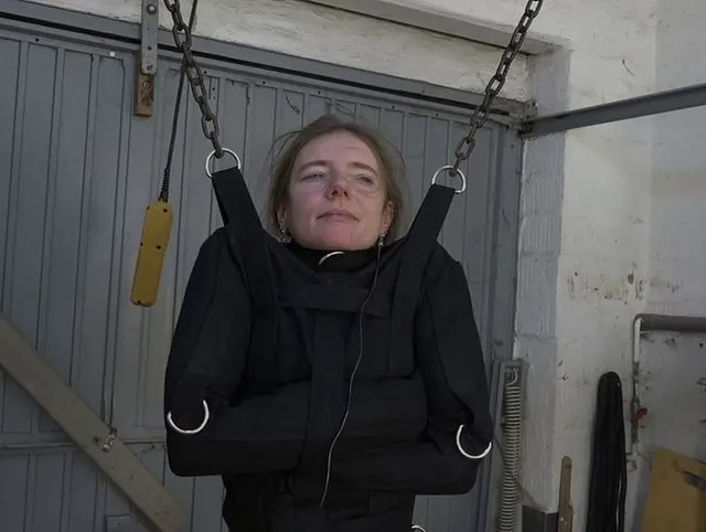 In Maske und Zwangsjacke hängend die Möse bearbeitet